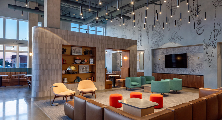 Lounge with colorful chairs, leather sectional couch, shelves with decor, and TV.