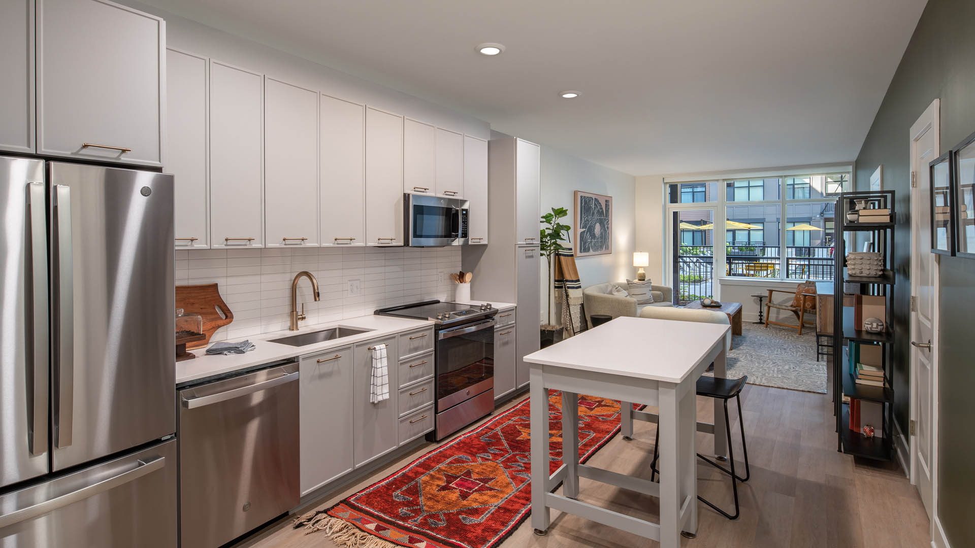 Kitchen with wood floor, white cabinets and counters, and stainless steel appliances.
